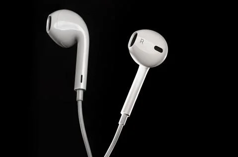 Proffessional close up of white earbuds isolated agains black background with Stock Photos