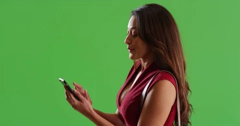 Profile of beautiful Latina female messaging on smart phone on green screen Stock Footage