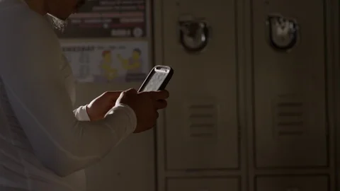 Profile of boxer messaging on mobile phone standing in locker room 스톡 동영상 104539946