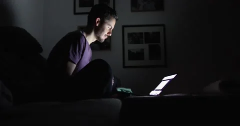 Profile of a brunette with a beard in the dark in front of a laptop screen Stock Footage 130489441