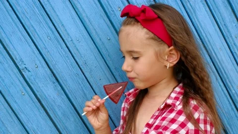 Profile of a child licking a red triangular candy on a stick. Stock Footage 171137264