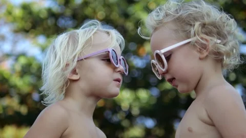 Profile close-up view, sibling twin sister babies kiss each other expressing Stock Footage 240894154