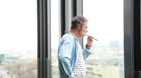 Profile of creative director standing by window, smoking electronic cigarette Stock Footage 59544555