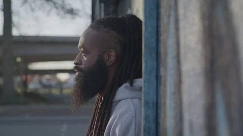 Profile of Diverse Man with Dreadlocks and Beard Looking up Outdoors at Sunset Stock Footage 270397468