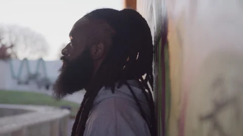 Profile of Diverse Man with Dreadlocks Looking up While Leaning Against Downtown Stock Footage 270399494