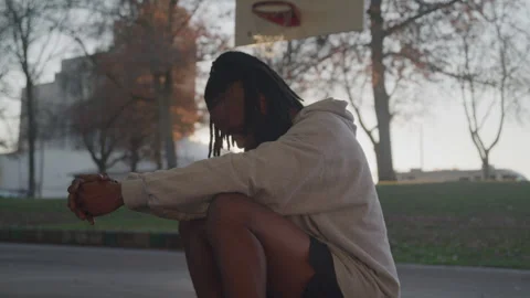 Profile of Diverse Man with Dreads Taking a Break at Outdoor Court at Sunset Stock Footage 270398683