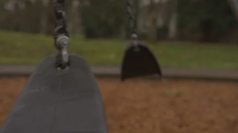 Profile of Empty Swings Moving on Their Own in an Empty Playground Stock Footage 208764225
