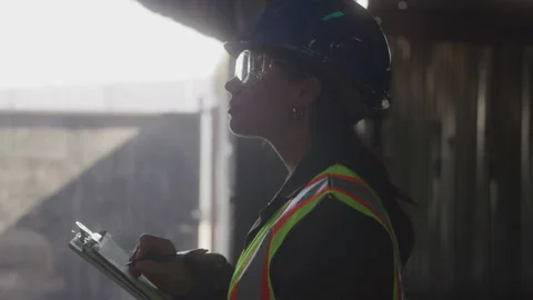 Profile of a Female Construction Worker in Safety Gear Writing on a Clipboard Stock Footage 208797448