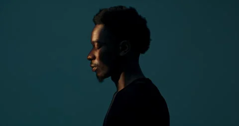 Profile of handsome attractive dark skinned male looking at light in darkstudio Stock Footage 260432415