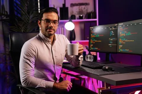 Profile IT looking camera holding coffee cup at neon cyber office. Surmise. Foto stock