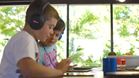Profile kids talking about tablet games.They wear headphones. Stock Footage 137522766
