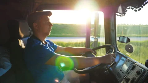 Profile of lorry driver riding through countryside at sunset time. Man in hat Stock Footage 115035415