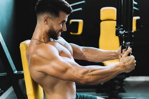 Profile of a man exercising with weights using a machine in a gym Stock Photos