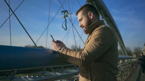 Profile of man writing message on smartphone on the footbridge  Vídeo Stock 72710621