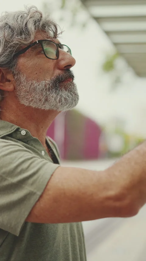 Profile of middle-aged man with gray hair and beard, runs his finger along the Stock Footage 227021896