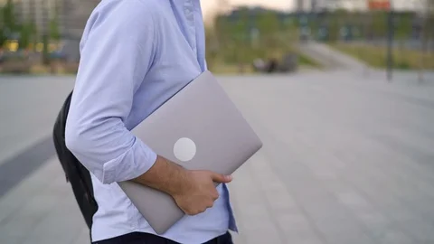 Profile middle shot of man in blue shirt walking with laptop, no face Vidéo 121850235