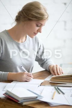 Profile portait of girl performing a written task in copybook Stock Photos