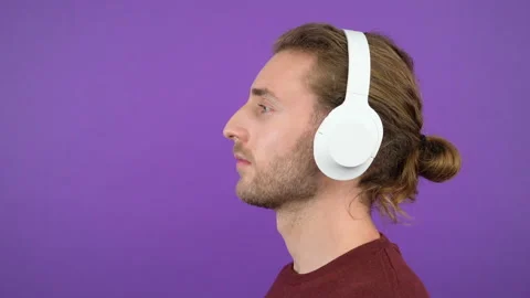 Profile portrait of a long-haired courageous man wearing large white wireless Stock Footage 145364081