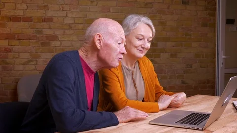 Profile portrait of two senior gray-haired caucasian colleagues having videocall Video stock 108860782