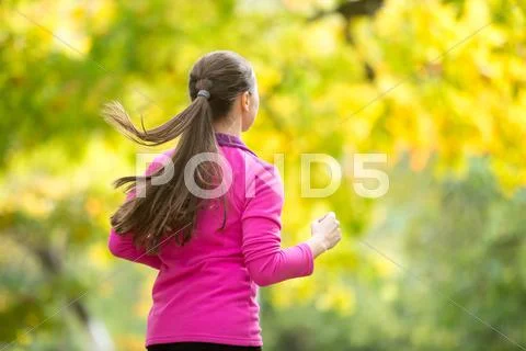 Profile portrait of a young attractive woman jogging in the autu Stock Photos