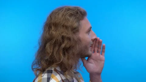 Profile portrait.long-haired curly man on an isolated blue background. Man tells Stock Footage 138032753