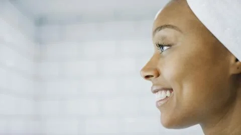 Profile shot of beautiful woman smiling in the mirror about to do her make up Stock Photos