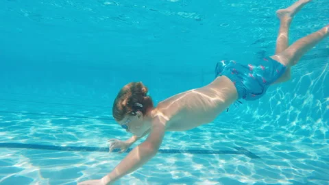 Profile side view of 10 year old boy swimming under water in large lap pool Stock Footage 248081840