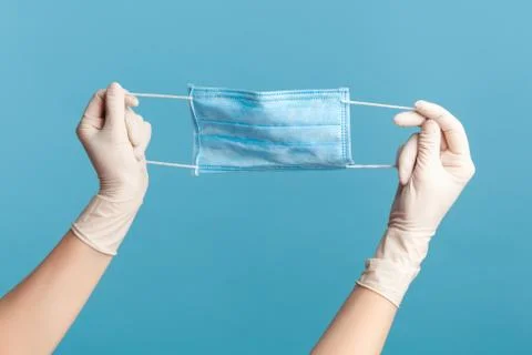 Profile side view closeup of human hand in white surgical gloves holding blue Foto stock