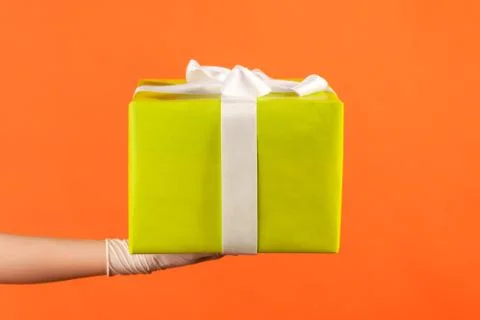 Profile side view closeup of human hand in white surgical gloves holding gift Stock Photos
