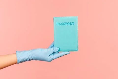 Profile side view closeup of human hand in blue surgical gloves holding passp Foto stock