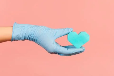 Profile side view closeup of human hand in blue surgical gloves holding small Foto stock