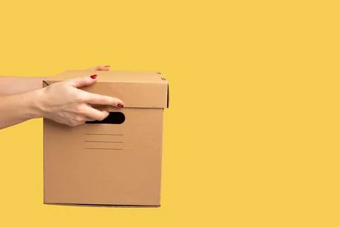 Profile side view closeup of human hand holding cardboard box, carton parcel Stock Photos