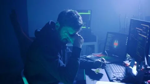 Profile of stressed hacker trying a virus attack on corporate servers in dark Stockfoto's