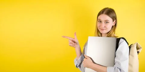 Profile studio shot wuth happy female student holding laptop and pointing at  Stock Photos