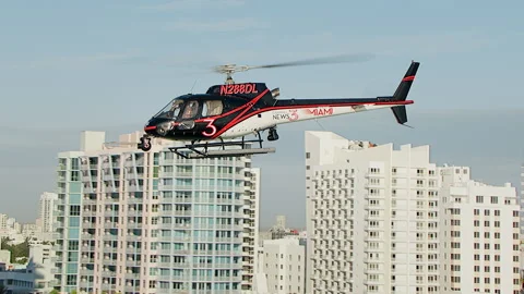 Profile tracking with chopper from side past Miami apartments Stock Footage 136198239