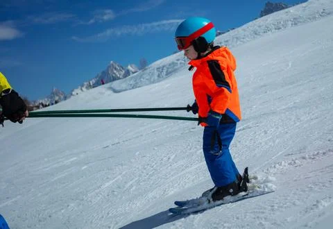 Profile view of child learn to ski with instructor holding poles Stock-Fotos