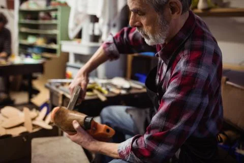 Profile view of cobbler stapling a shoe in his workshop 写真素材