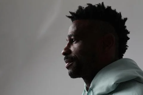Profile view of dark skinned man wears casual outfit. Good emotions concept. Photos