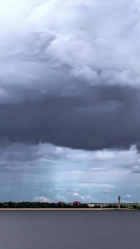 Profile view of dense, thick clouds moving prior to rainfall over a river. Time Stock Footage 317625924