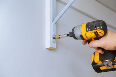 Profile view of a good looking handyman making some drill wall installing a s Foto stock