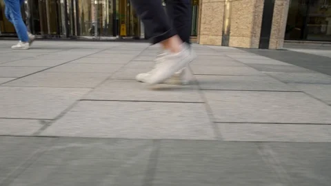 Profile view from ground level of white men sneakers walking along pavement Stock Footage 117351628