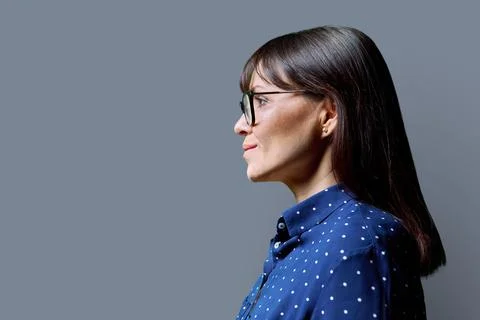 Profile view of middle aged smiling woman, gray background, copy space Stock Photos