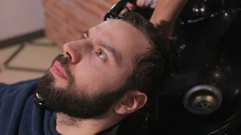 Profile view of a young arabic man getting his hair washed and his head massaged Stock Footage 93710454