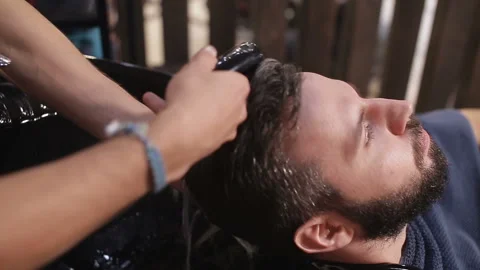 Profile view of a young arabic man getting his hair washed and his head massaged Stock Footage 93710558