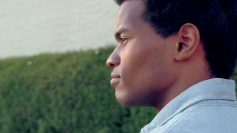 Profile view of young, handsome, African American man walking outside of a mall Stock Footage 74128656