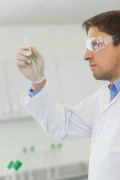 Profile view of young male scientist looking at small test tube Stock Photos