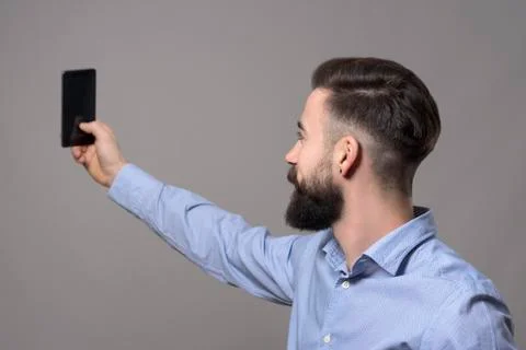 Profile view of young modern handsome bearded business man taking selfie phot Stock Photos
