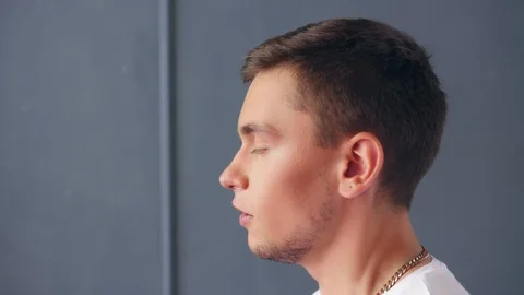 Profile view of young singing man against grey background. Close up shot. Stock Footage 118894308