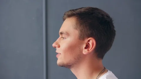 Profile view of young singing man against grey background. Close up shot. Video stock 118894433