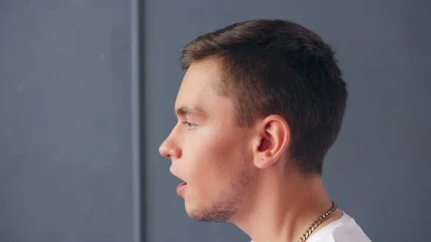 Profile view of young singing man against grey background. Close up shot. Stock Footage 118894437